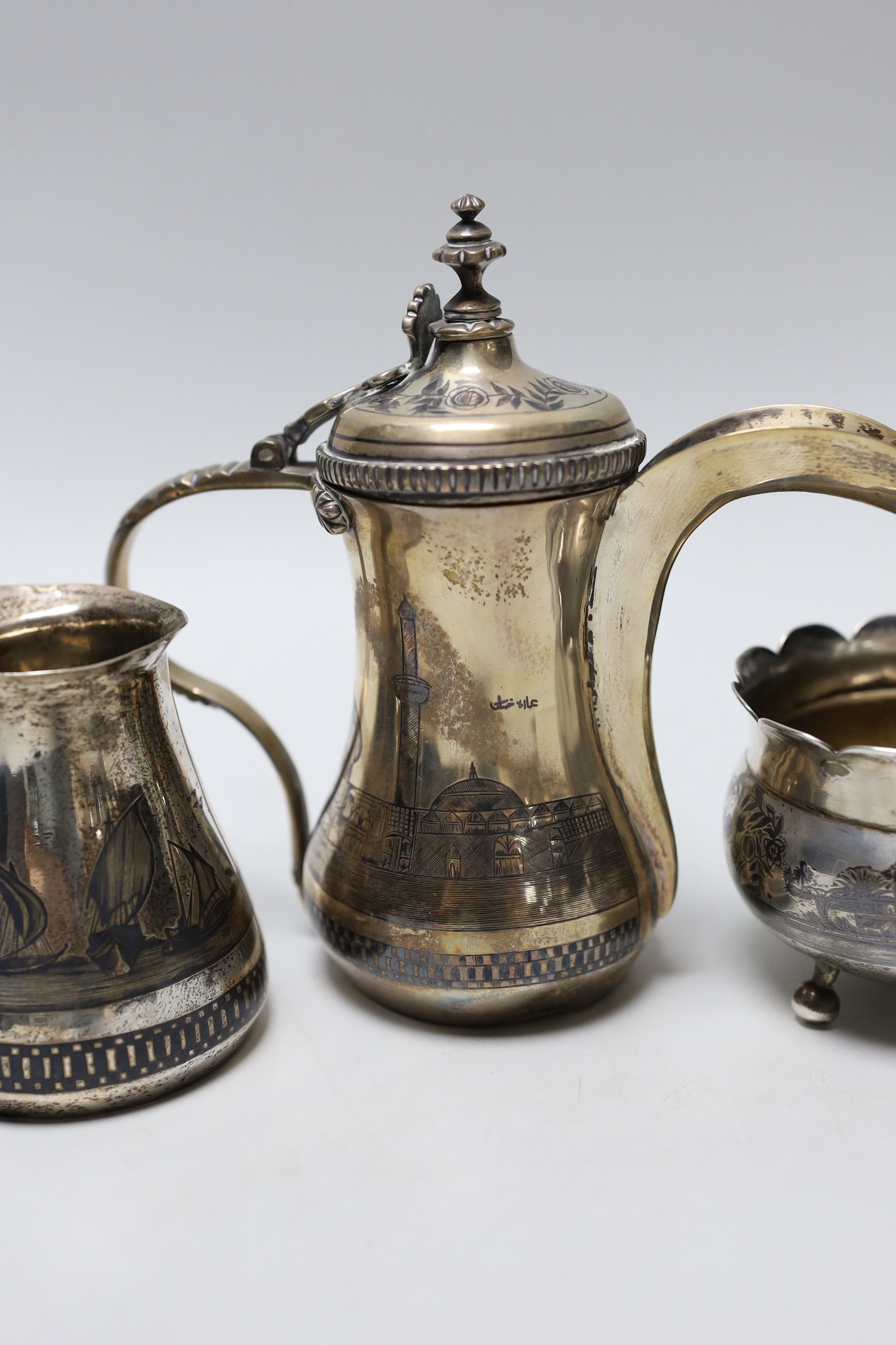 A Middle Eastern white metal and niello cream jug, a sugar bowl and coffee pot, 16.4cm, gross weight 22oz.